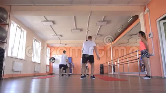 白种人的男性朋友在一个现代健身中心在一个美丽的女孩的教练的帮助下运动团体健身视频的预览图