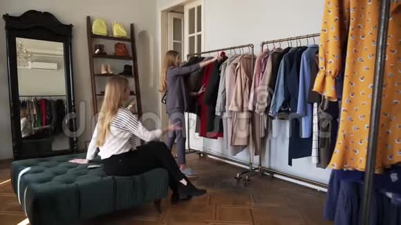 两个女孩或双胞胎姐妹一起购物长发金发的年轻金发女性站着试着穿一件新的黑色外套视频的预览图