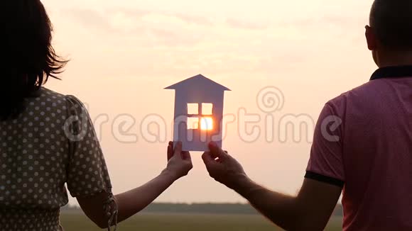 夕阳下纸屋的剪影一男一女抱着纸房看夕阳A视频的预览图