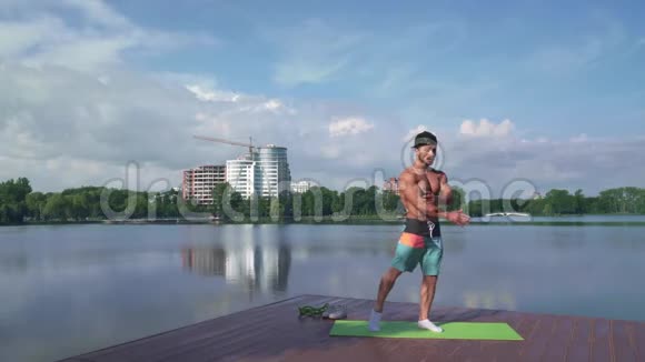 健美运动员在湖边的摄像机上展示他肌肉发达的身体视频的预览图