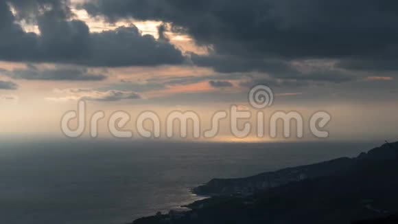 日落时分在岩石海岸附近的海面上有着太阳的暗云视频的预览图