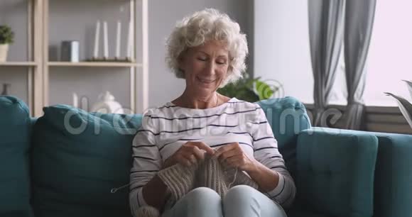 微笑的老奶奶编织围巾享受休闲的爱好视频的预览图