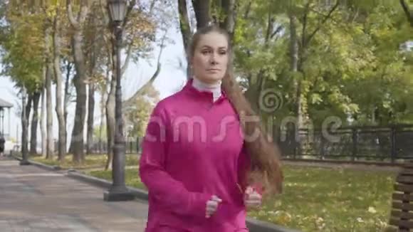年轻的高加索女人穿着粉红色运动服因为胸痛而在跑步过程中停下来女生跑步时感觉不好视频的预览图