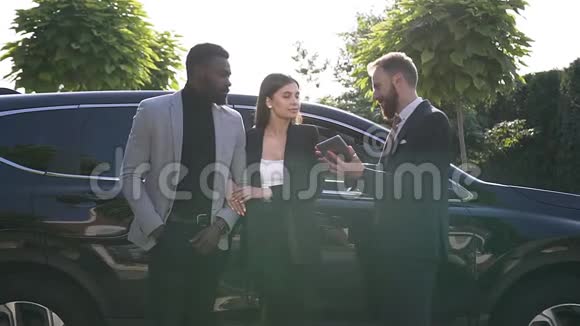 售货员在户外给年轻夫妇介绍一辆新车成功的汽车经销商告诉车主视频的预览图