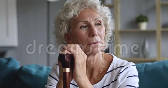 沮丧的老妇人拿着拐杖坐在沙发上视频的预览图