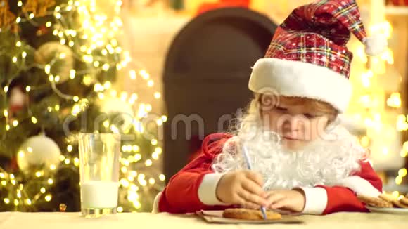 小圣诞老人抱着巧克力饼干的肖像圣诞老人长胡子的有趣的孩子家里的圣诞老人圣诞节视频的预览图