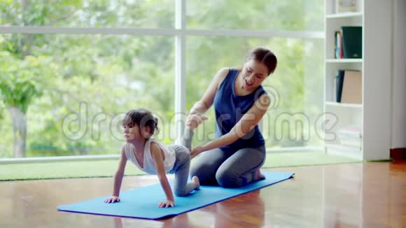 年轻的母亲训练她可爱的女儿锻炼身体视频的预览图