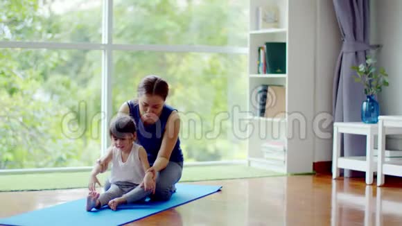 年轻的母亲训练她可爱的女儿锻炼身体视频的预览图