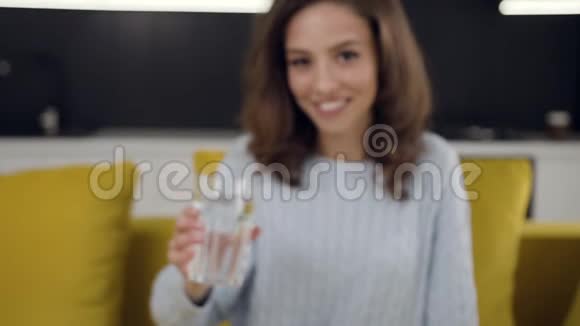 30岁的漂亮的微笑女士用一杯纯净水在相机上摆姿势视频的预览图