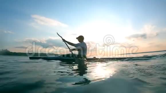 一个坐皮划艇的人正朝岸边划水视频的预览图