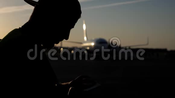 人在机场浏览智能手机的剪影背景是飞机视频的预览图