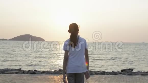 亚洲可爱的女孩悠闲地走向海岸在日出时举起双臂飞向空中视频的预览图