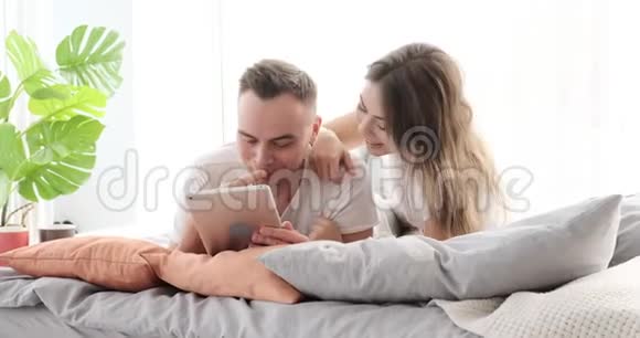 情侣在床上玩数字平板电脑视频的预览图