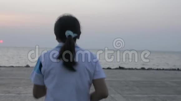 亚洲妇女慢跑到海岸后景早上在普吉岛将手臂举到空中视频的预览图