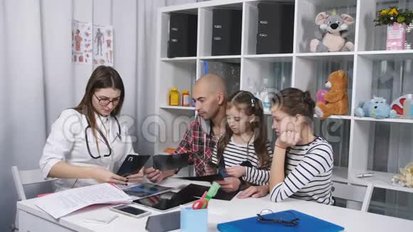 父亲和两个女儿在医生办公室征求意见父亲带女儿去看医生视频的预览图