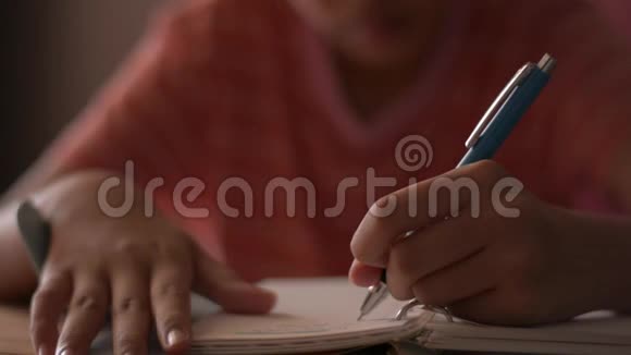 合上一个小女孩写在笔记本上的手女学童在日记上做笔记做作业视频的预览图