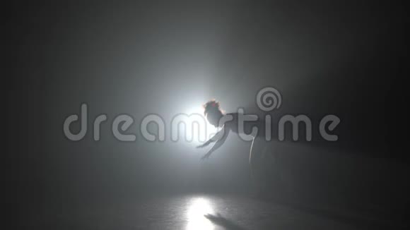 柯尔女性在黑暗中练习卡波伊拉在演播室的灯光聚光灯下视频的预览图