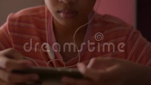 亚洲小女孩在家里看网上媒体时用手机带耳机视频的预览图
