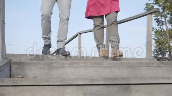 镜头跟随男人和女人的腿走下楼梯在户外年轻夫妇在秋天公园散步约会视频的预览图
