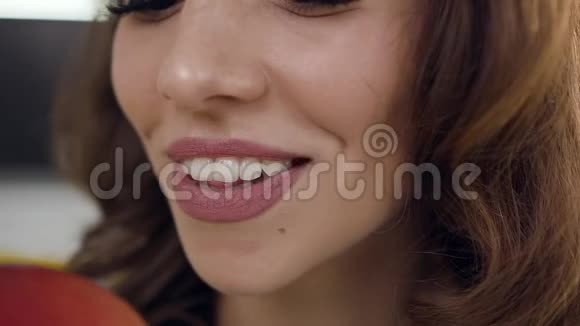 美丽快乐精力充沛的女士用健康的牙齿咬着红多汁的苹果用可爱的微笑镜头前视频的预览图
