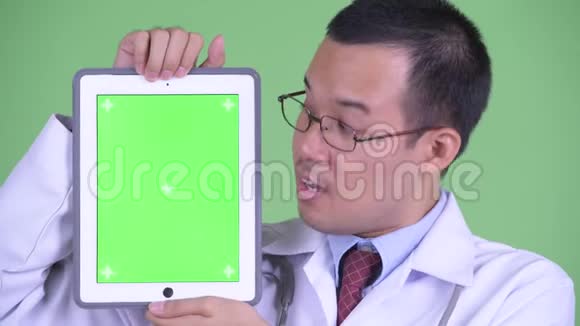 快乐的亚洲男子医生展示数码平板电脑的脸视频的预览图