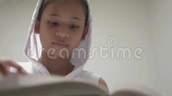 可爱的微笑的年轻女孩穿着白色的头巾衬衫在图书馆看书漂亮的女青少年喜欢搜索有用的信息视频的预览图