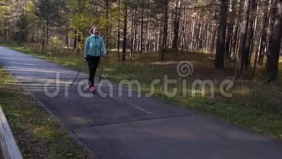 女人在秋天的公园里练习北欧散步从附近的一辆车上运动对角线正面视图视频的预览图