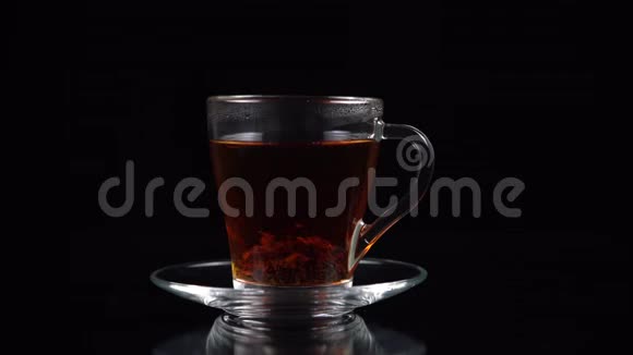 在一杯茶茶中茶叶省略了柠檬片粗糙地放在黑色背景上视频的预览图