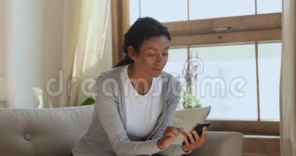 年轻的非洲女士在家里使用手机应用程序视频的预览图