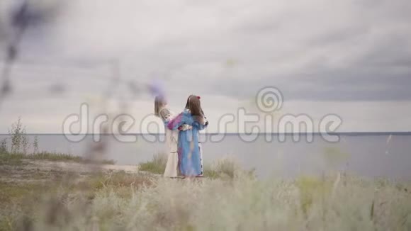 三个女朋友穿着漂亮的长裙刺绣在河前旋转概念视频的预览图