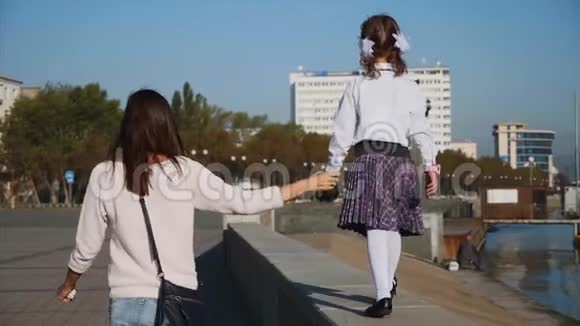 女学生正和妈妈一起走在海滨的栏杆上坐稳了后景视频的预览图