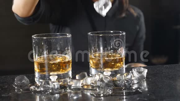 夜总会的饮料夜间生活观念酒保用酒精饮料将冰块倒入玻璃杯中的特写镜头视频的预览图