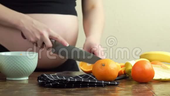 孕妇在厨房里做健康的零食香蕉和橘子切片视频的预览图