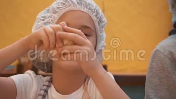 小女孩戴着一次性帽子在厨房里玩生面团快乐的女孩手里拿着面团在烹饪大师手里视频的预览图