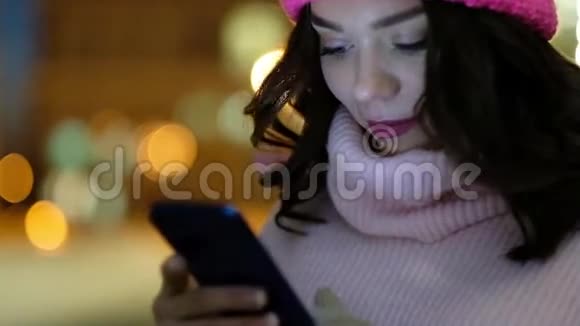 年轻漂亮的女人晚上在城里用手机视频的预览图