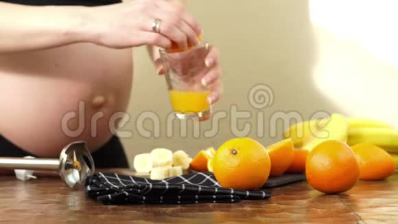 怀孕三个月的孕妇准备一些新鲜的橙汁制成健康的水果奶昔视频的预览图