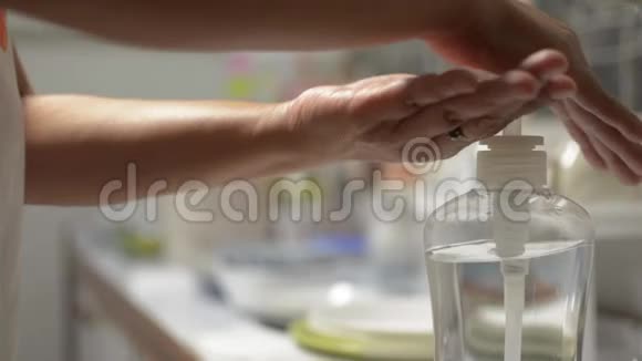 女人在COVID19疫情期间用酒精凝胶洗手家庭主妇清洗厨房用具视频的预览图