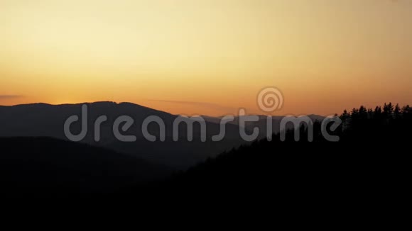 朦胧的粉红色和黄色的日落山地景观黑暗的森林轮廓视频的预览图
