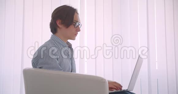 特写侧景照片年轻成功的高加索商人在笔记本电脑上工作看着坐在里面的相机视频的预览图