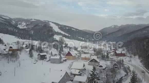 在喀尔巴阡村的冬季公路上行驶到滑雪胜地Pilipets的汽车的鸟瞰图鸟雪的视野视频的预览图