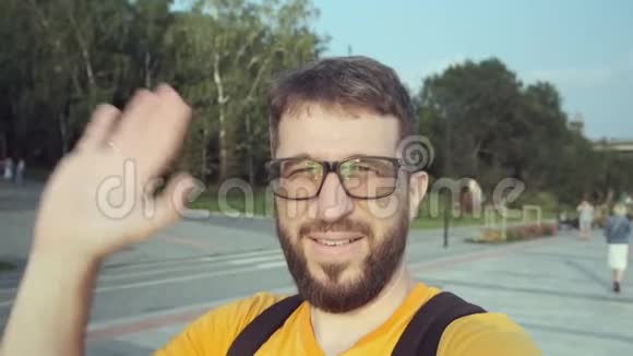 带着眼镜和胡子的快乐男性博客作者在街上对着镜头说话视频的预览图