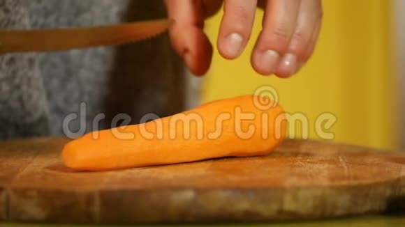 女性手用橙色的刀慢慢地砍胡萝卜视频的预览图