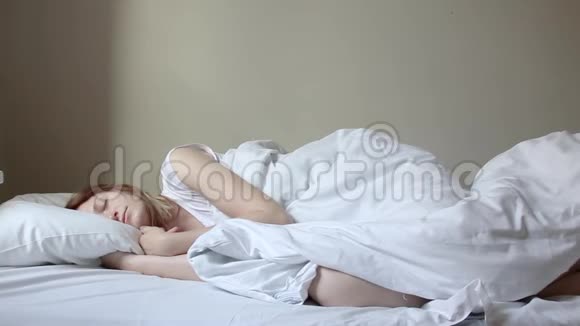 美丽的金发女郎在早晨慢慢醒来伸展身体从床上站起来视频的预览图