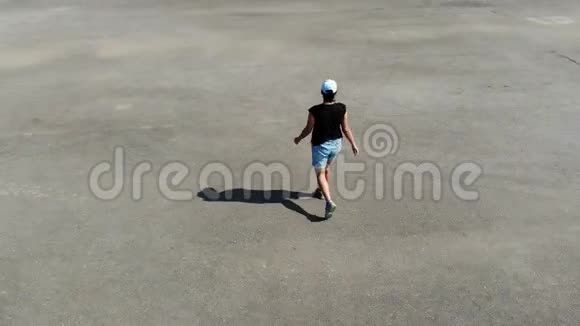 在荒芜的沥青操场上独自行走的女人的空中景色人们的生活方式体育活动孤独视频的预览图
