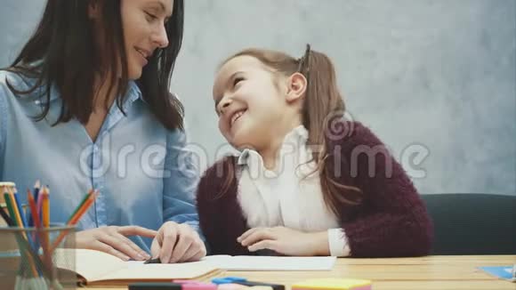 妈妈和女儿的灰色背景在这期间妈妈微笑着交流女儿写作业妈妈抱着她视频的预览图