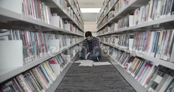 大学生坐在图书馆的地板上看书翻书页中弹视频的预览图