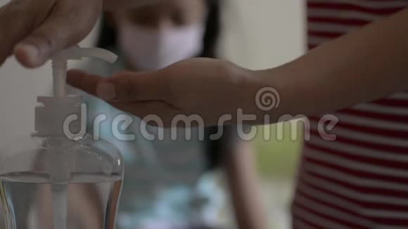 母亲用酒精凝胶清洁她的手并在接近和拥抱她的女儿之前戴上保护面具视频的预览图