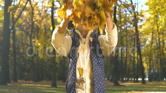 活泼开朗的小女孩在镜头前缓慢地抛出秋叶视频的预览图