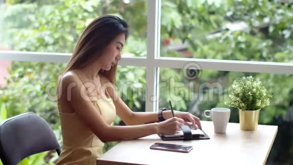 年轻漂亮的女人在咖啡店写预约书视频的预览图