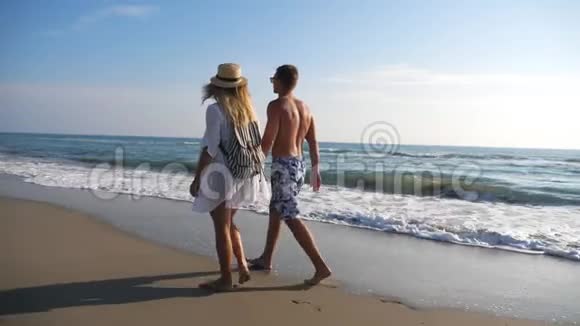 在度假胜地休息时一对情侣牵着手在海岸散步男人和女人在海滩上漫步享受视频的预览图